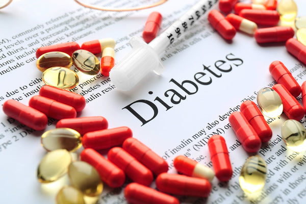 Diabetes text on a paper document surrounded by vitamins and red medicine pills
