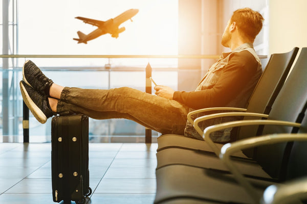 Hombre sentado en una silla con los pies en el equipaje mirando el avión