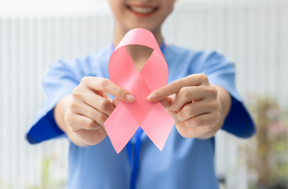 Mujer sostiene una cinta rosa que simboliza la lucha contra el cáncer de mama